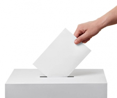 immagine sfondo bianco con mano che inserisce scheda elettorale nell&#039;urna